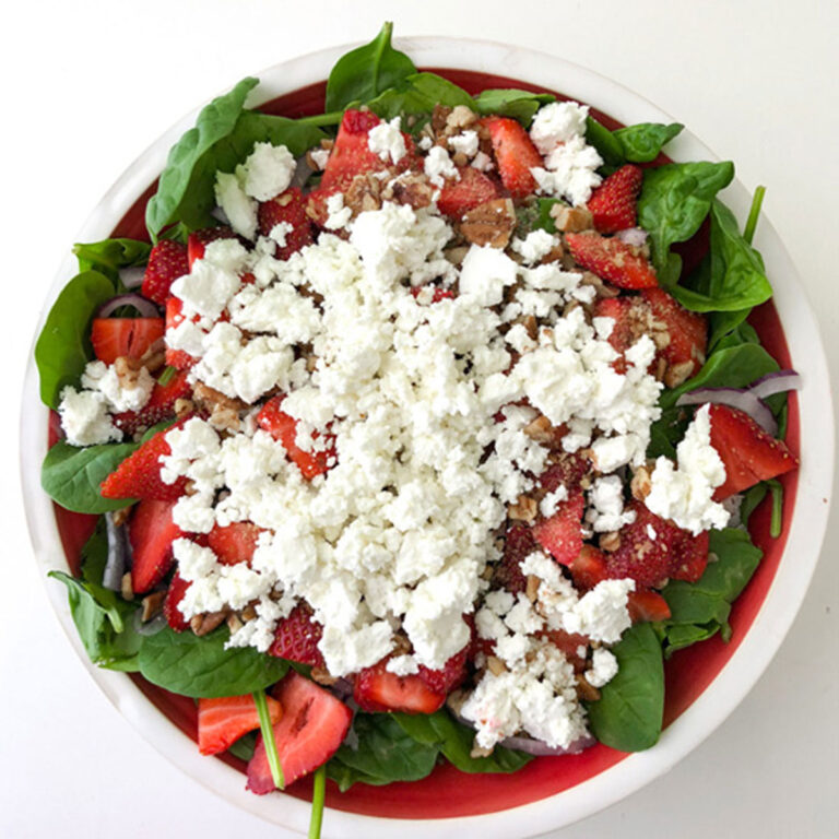 Strawberry spinach salad on white counter to the right of the picture
