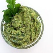 Poblano and Green Chile Guacamole in clear bowl on white table