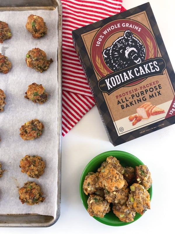 sausage balls baked on a baking sheet with a box of kodiak cakes baking mix next to it.