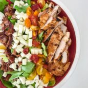 BBQ Chicken Cobb Salad with Herb Yogurt Dressing in a red bowl on a white table