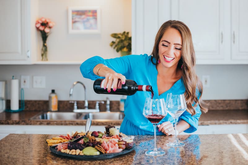 me pouring a glass of wine in my kitchen for august wine down wednesday post