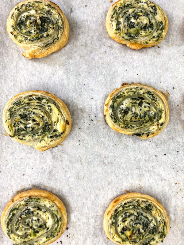 spinach and artichoke puff pastry rolls on a baking sheet after they have baked. 
