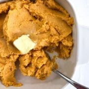 Whipped Ricotta Sweet Potatoes in a square dish with a pad of butter and spoon in it