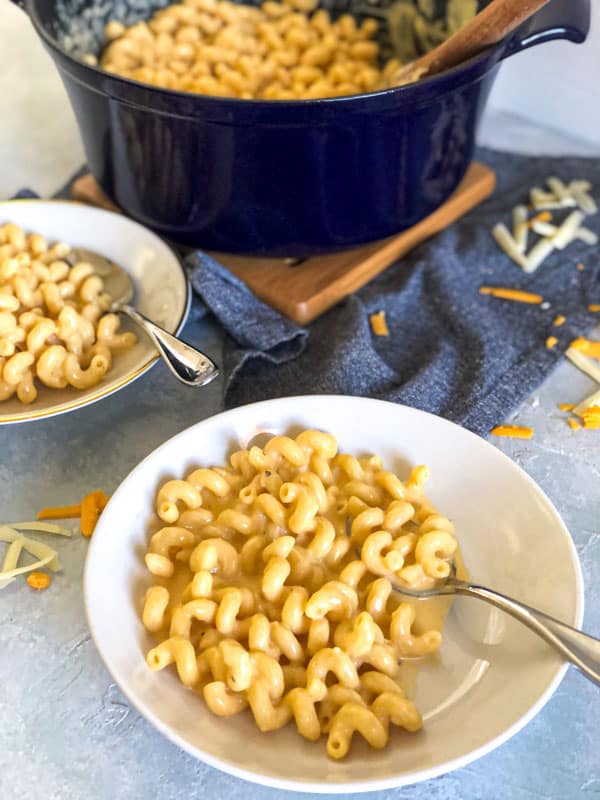 2 bowls of Southern Cheddar Mac and Cheese with the pot in the background