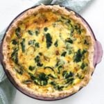 Caramelized Onion & Spinach Quiche on a white table with green napkin