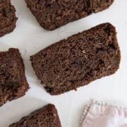 5 slices of chocolate zucchini bread on a white table with a pink napkin in the bottom right corner