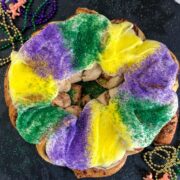 decorated king cake on a black plate with beads