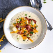 Instant Pot Potato Soup in a white bowl with toppings and a blue napkin