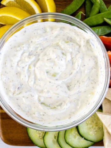 Tzatziki Sauce in a bow in front on gyros and pitas