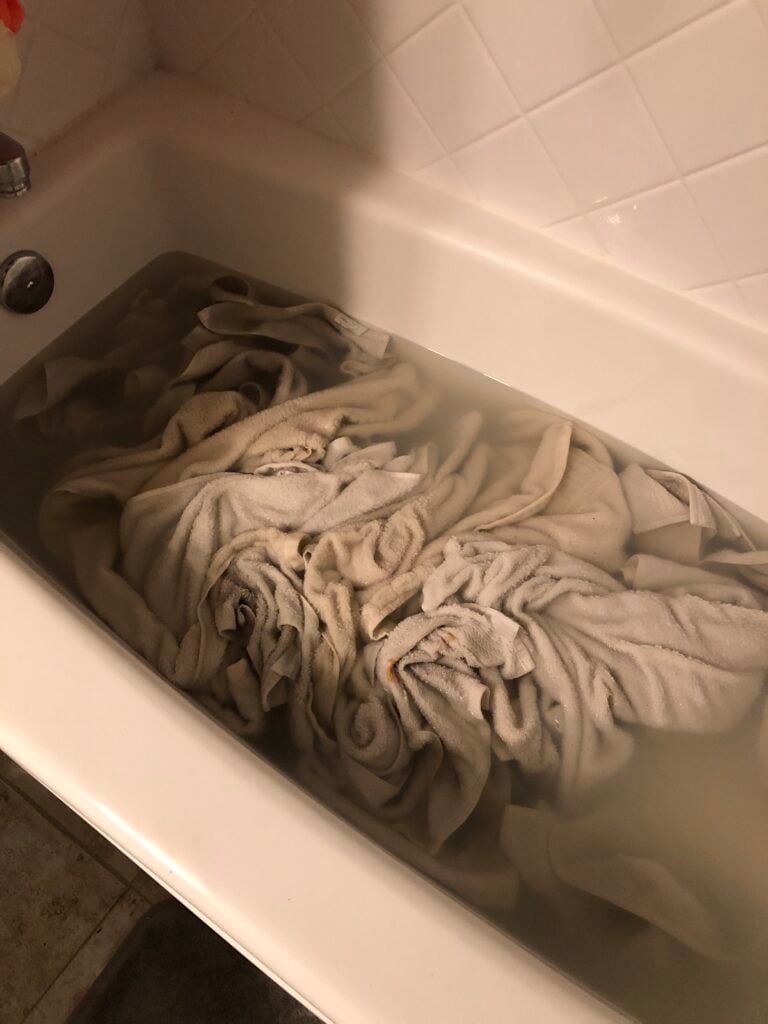 tub full of water and white towels for stripping laundry