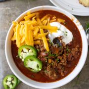 bowl of chili con carne with jalapenos and corn bread around it