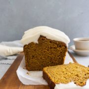 pumpkin loaf with cream cheese icing sliced on a cutting board