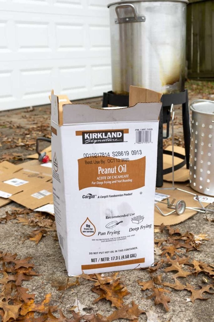 box of peanut oil in front of a turkey fryer set up outside - How to Fry a Turkey