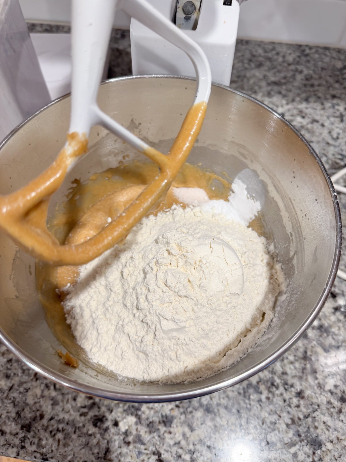 Adding in flour for mixing together cookie dough. 