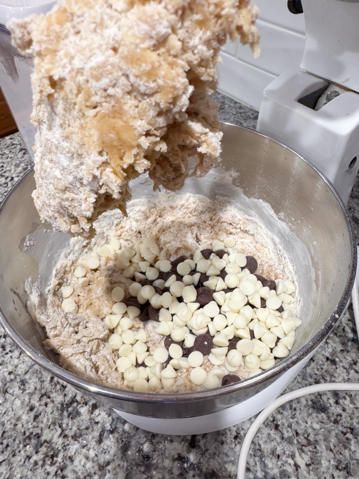 Adding in chocolate chips in a stand mixer while making cookie dough. 
