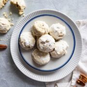 pecan sandies on a plate with cookies and pecans around the plate