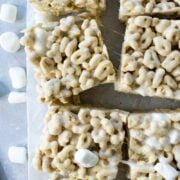 Cereal Marshmallow Bars sliced on parchment paper with extra marshmallows around
