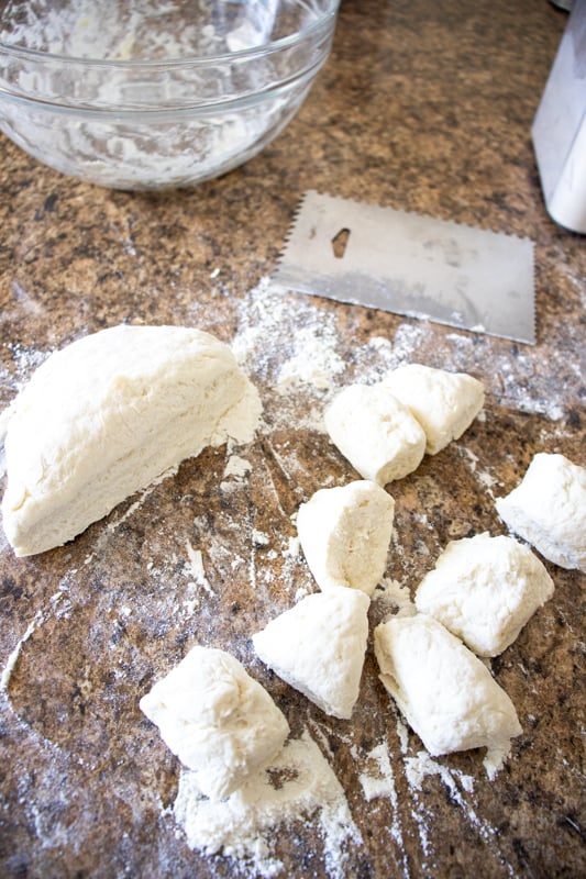 Cutting our small pieces of dough on a counter top for bagel bites.