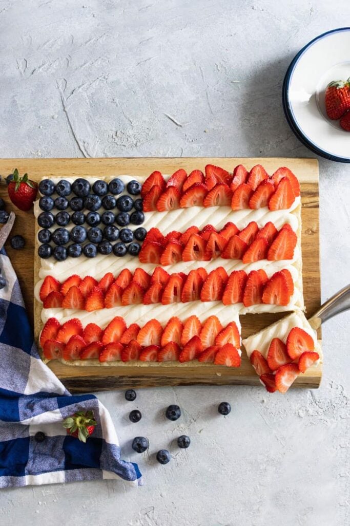 Red White and Blue Fruit Pizza with a corner cut. plate and napkins around it.
