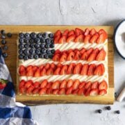 Red White and Blue Fruit Pizza on a cutting board with plates and a napkin