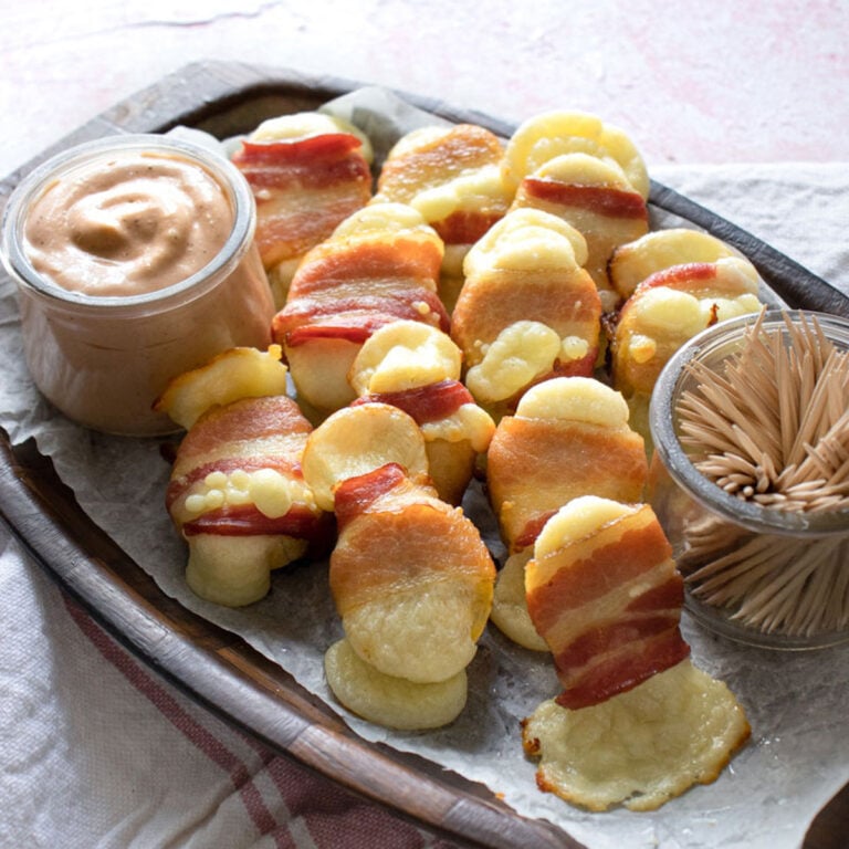 Cheesy Bacon Wrapped Plantain Bites with Guava Crema Dip on a wooden platter