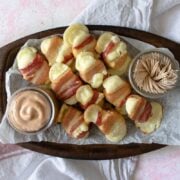 Cheesy Bacon Wrapped Plantain Bites with Guava Crema Dip on a wooden platter