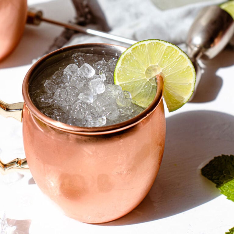 3 copper mugs with mexican mule in them and a tequila bottle in the background