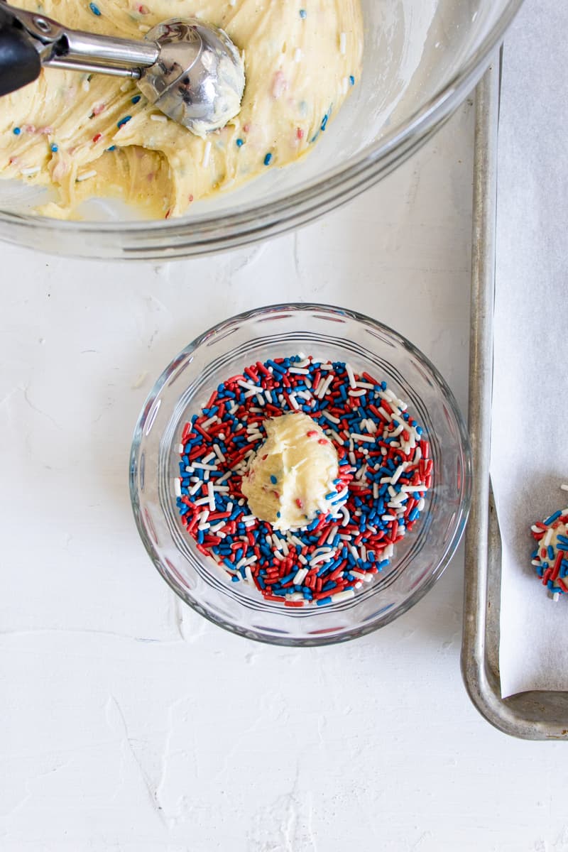 rolling cookie dough in a bowl of sprinkles