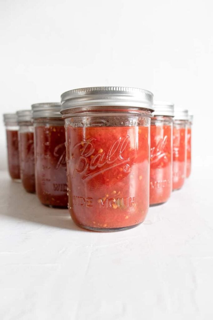 mason jars full of tomatoes on a white background for How to Can Tomatoes