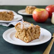 brown butter apple bars on white plates with a gold fork and apples next to it