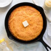 cast iron skillet cornbread with honey, plated, and butter next to it