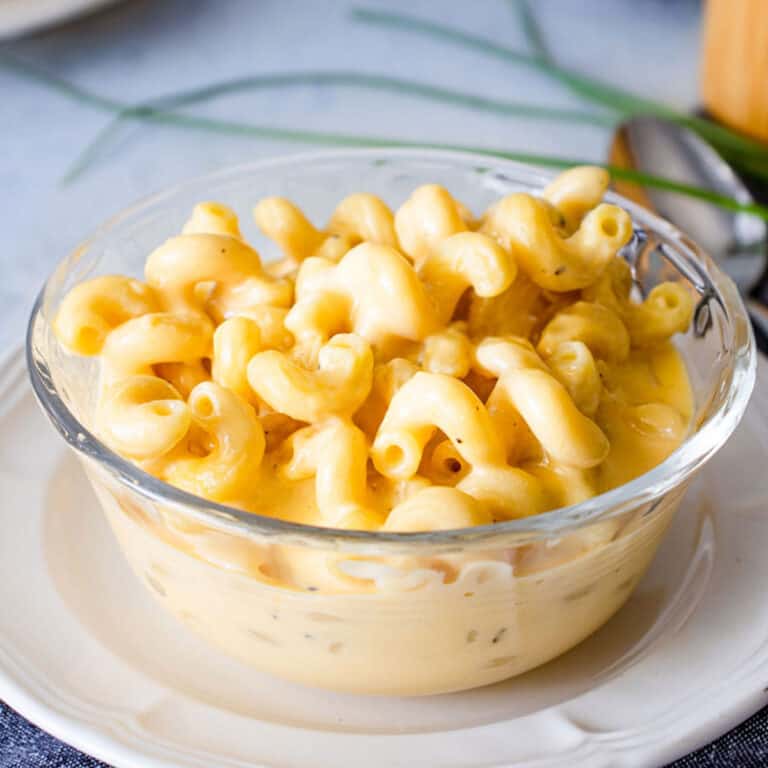 big bowl of southern cheddar mac & cheese with a blue napkin and chives next to it.