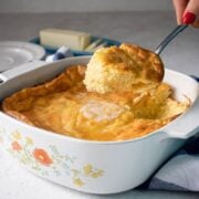 me scooping out a serving of southern spoon bread from a casserole dish