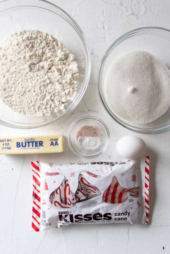 bowl of flour, sugar, and salt. a stick of butter, an egg, and a bag of Hershey's candy cane kisses