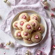 candy cane kiss cookies on a platter with kisses and lights next to it