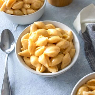 3 bowls of Mac and cheese with a spoon next to it.