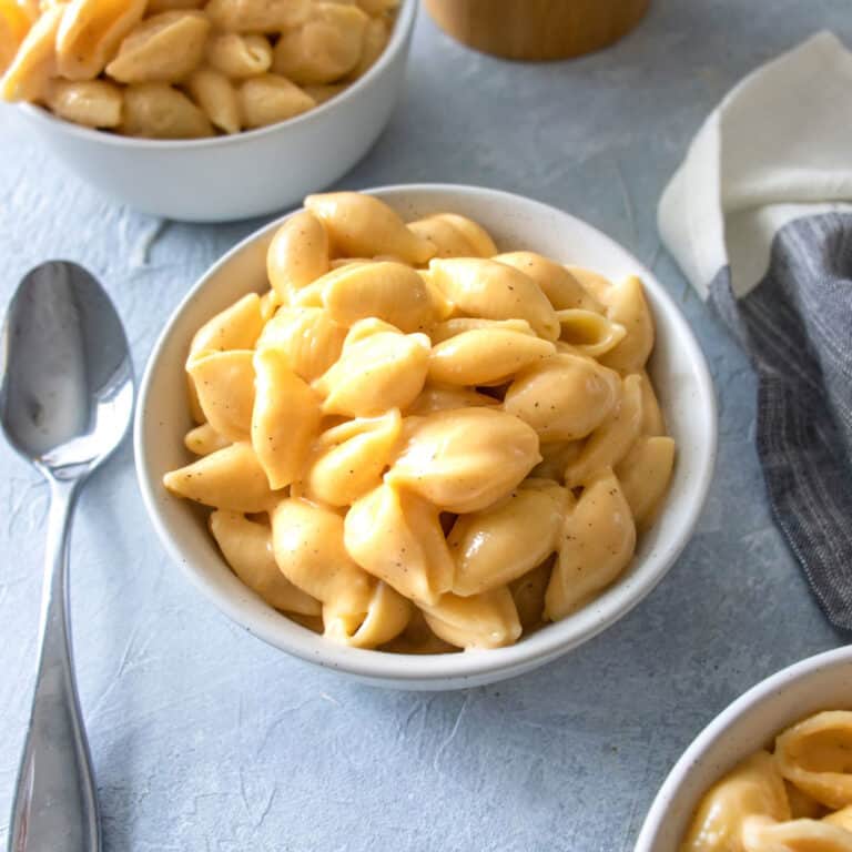 3 bowls of Mac and cheese with a spoon next to it.
