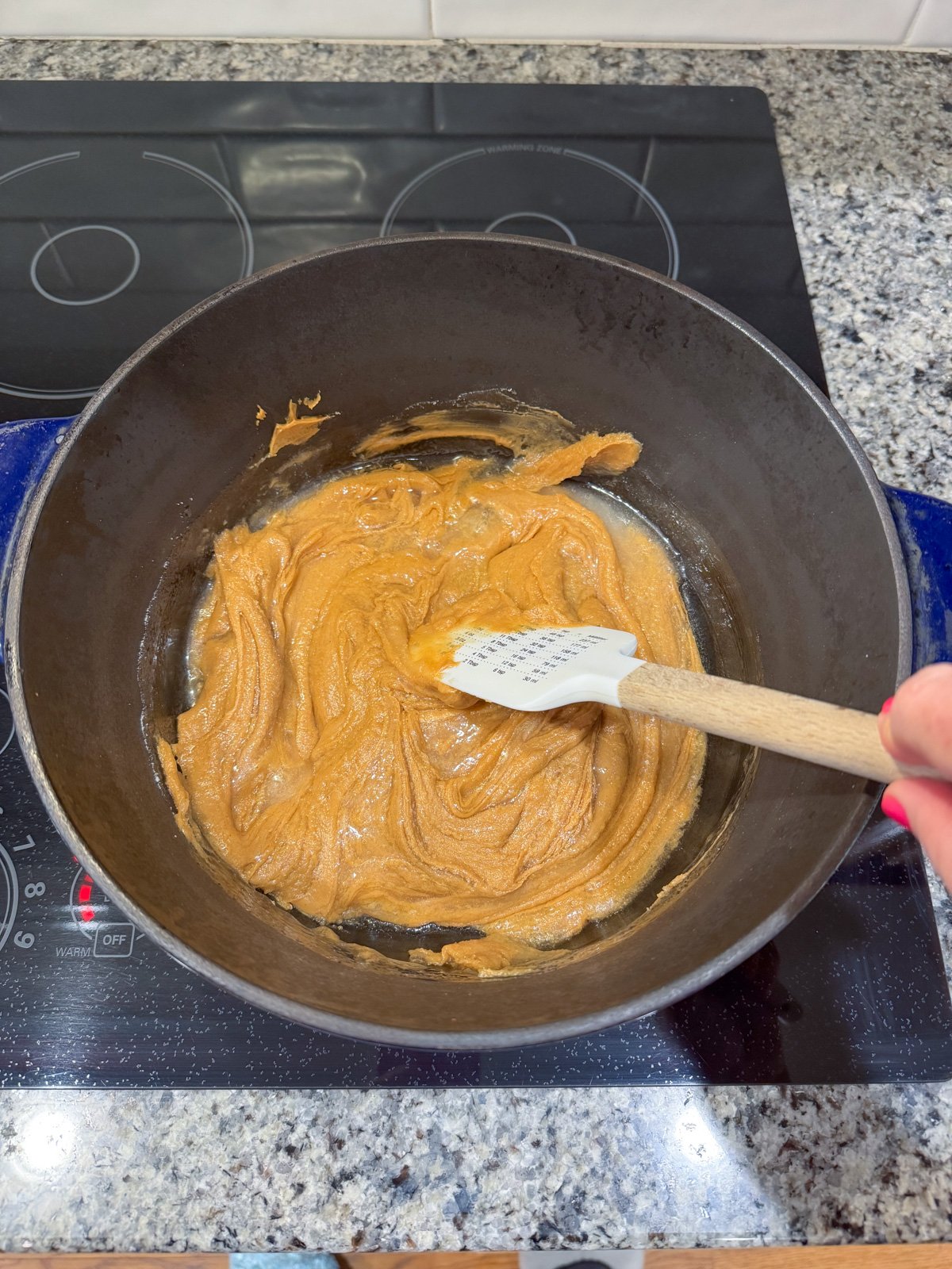 Stirring a sugar and PB mixture in a pot on the stove.
