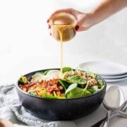 pouring hot bacon dressing on Hot Bacon & Mustard Spinach Salad