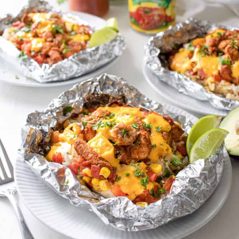 3 queso chicken foil packets on a plate.