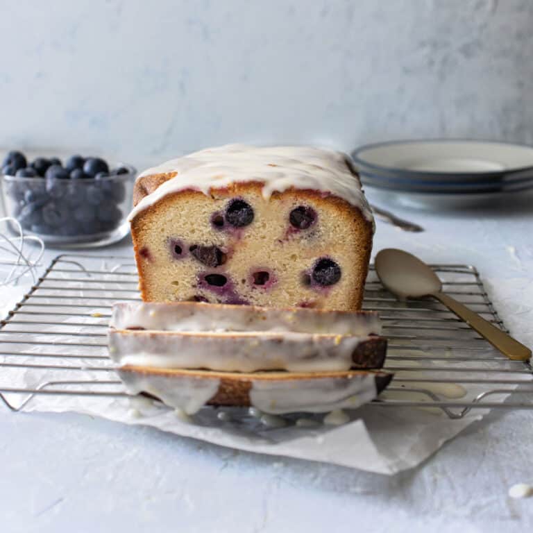 iced blueberry loaf sliced on a cooling rack.