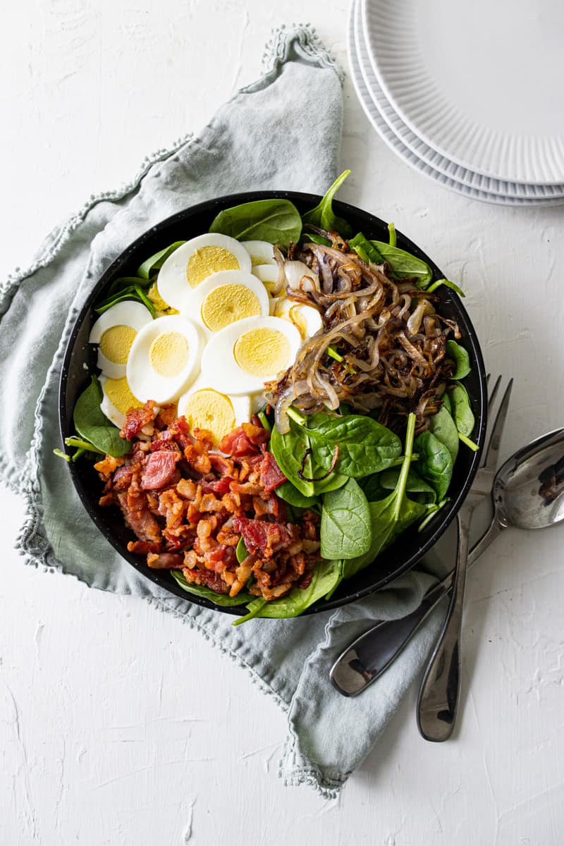 a big bowl of Hot Bacon & Mustard Spinach Salad without the dressing on it.