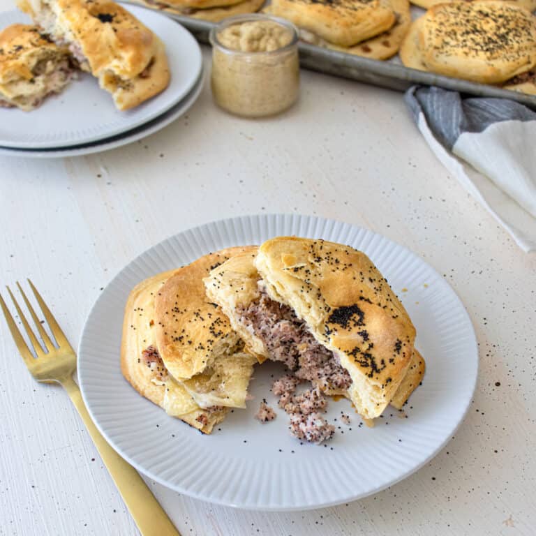a ham and swiss biscuit sandwich on a white plate with a gold fork.