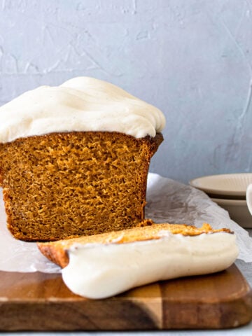 pumpkin loaf on a cutting board sliced iwth a fork and blue plates in the background