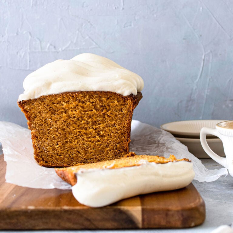 pumpkin loaf on a cutting board sliced iwth a fork and blue plates in the background