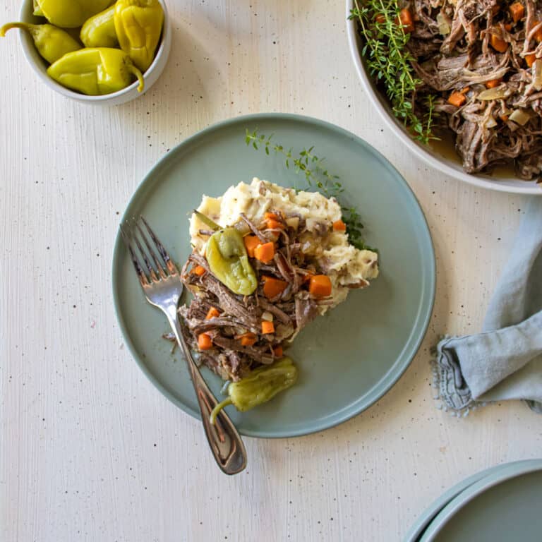 A plate of mashed potatoes and pot roast on top on a green plate.