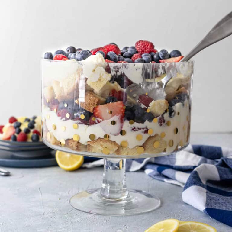 Summer berry trifle in a trifle dish with a big spoon in it.