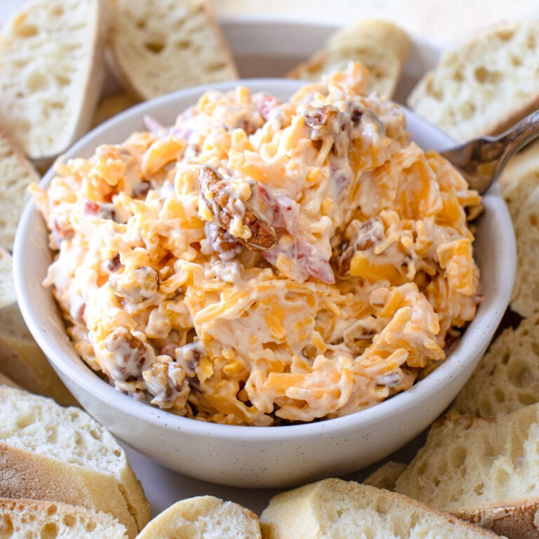 A big bowl of pimento cheese dip with French bread sliced around it.