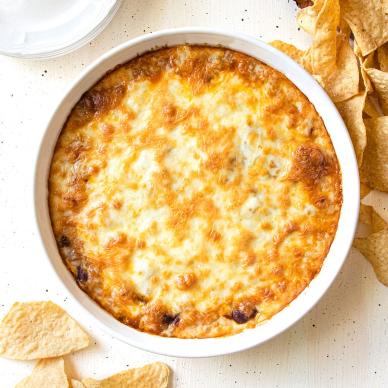 Chili cheese dip in a pie dish with chips around it.