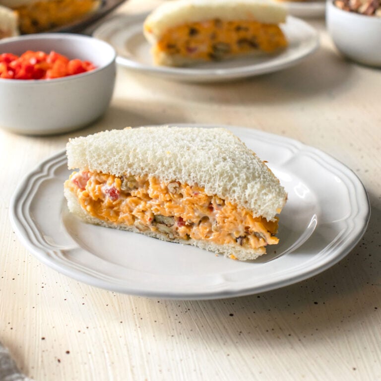 Pimento cheese sandwich on a white plate with more in the background.